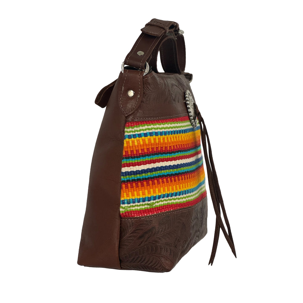 Side view of Maká Festive shoulder bag in brown with hand tooled leather, red themed hand woven tapestry, and bolo concho with tassle