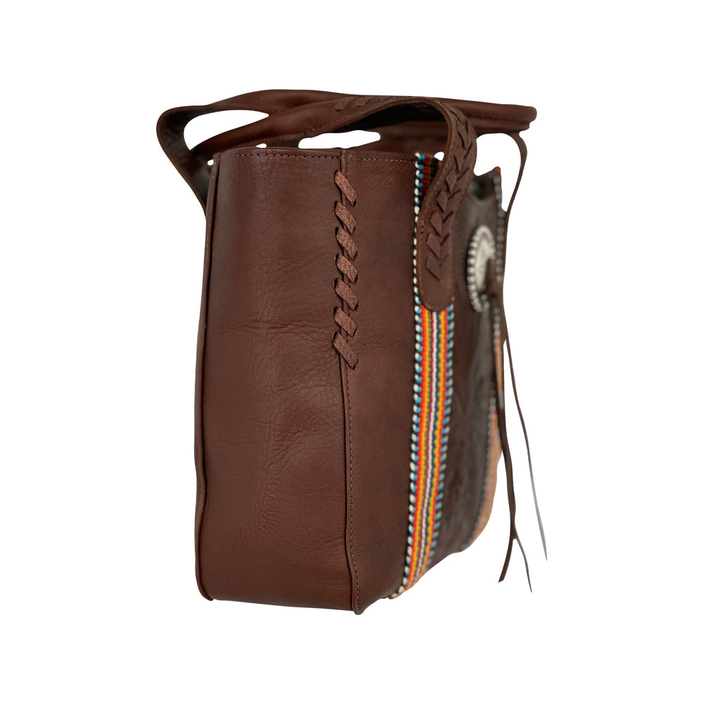 Side view of Maká Festive tote in brown with hand tooled leather, red themed hand woven tapestry, and bolo concho with tassle