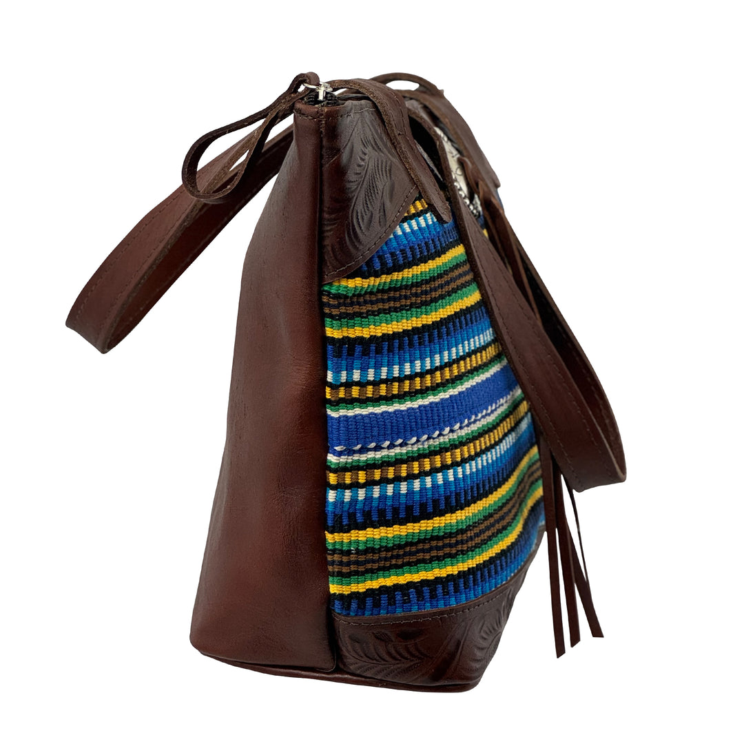 Side view of Maká Festive tote in brown with hand tooled leather, blue themed hand woven tapestry, and bolo concho with tassle