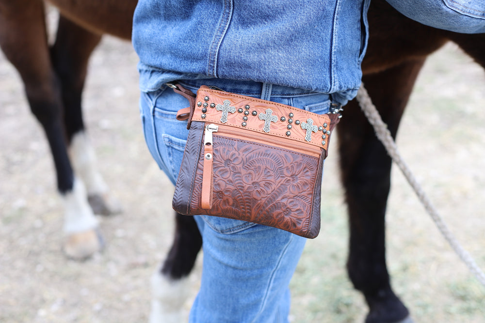 Lifestyle of crossbody/hip bag with hand tooled leather accents with model wearing it hooked to belt loops