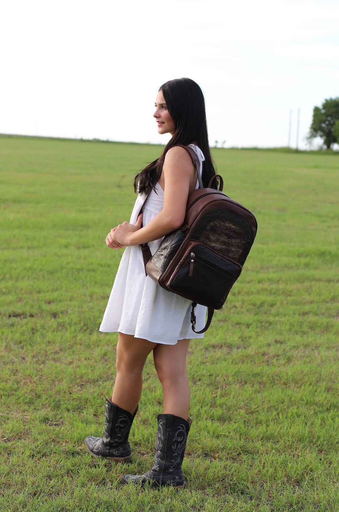 Lifestyle with model of Classic Travel backpack with hair-on hide in dark brown with hair-on hide accent and hand tooled leather trim