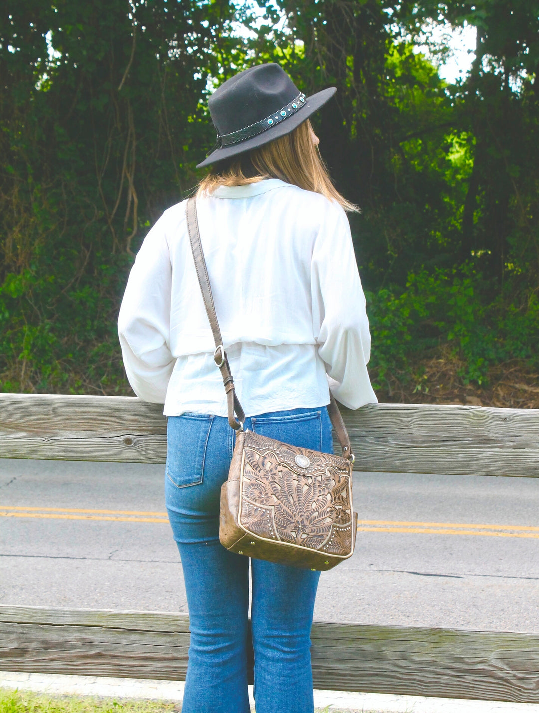Lifestyle with model of Inlay Eagle crossbody bag in distressed charcoal brown with hand tooled leather and cut out accents