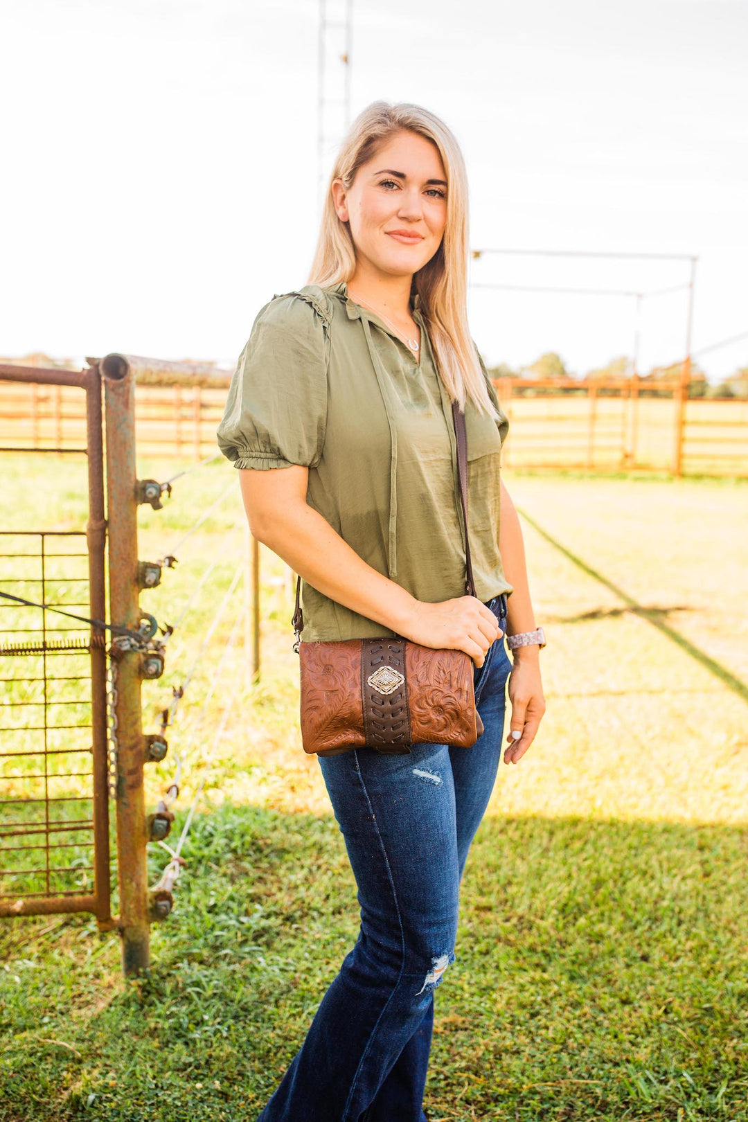 Lifestyle with model of Grab and Go crossbody foldover wallet/crossbody in dark brown with hand tooled leather accents and concho