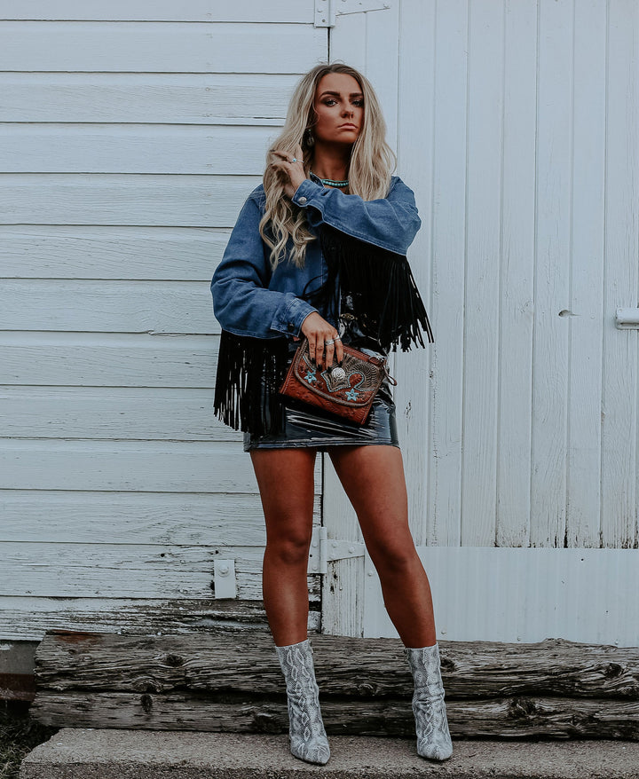 Lifestyle with model of Desert Wildflower crossbody bag in medium brown with hand tooled leather turquoise colored flower accents