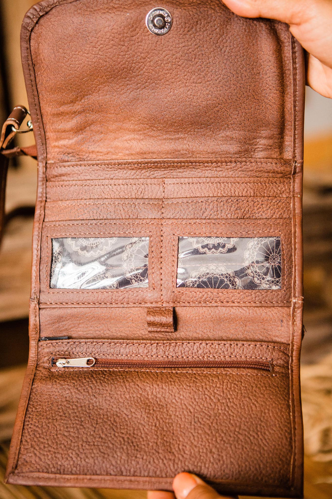 Lady Lace crossbody bag being held open by model with multiple card and slip pockets and clear id holder