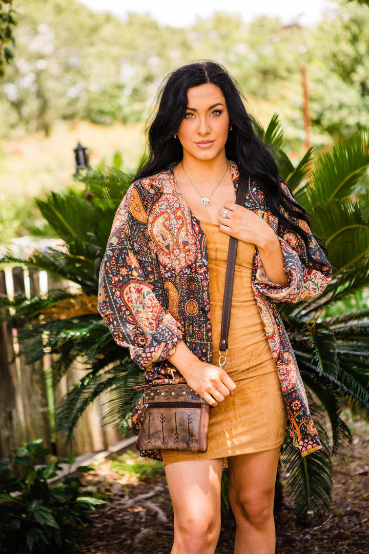 Lifestyle with model of Frontier Arrows crossbody/hip bag in distressed charcoal brown with hand tooled leather accents